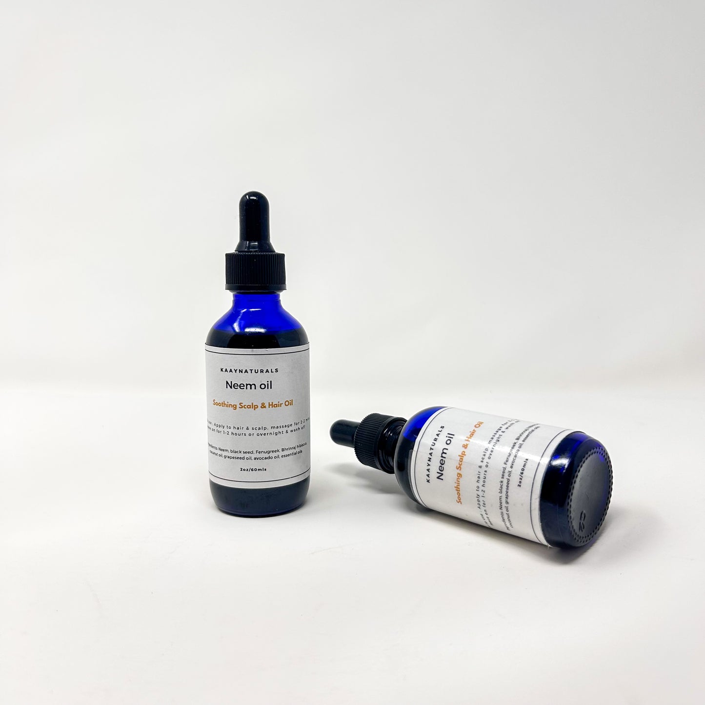 Two bottles of Neem oil with dropper lids on a white background