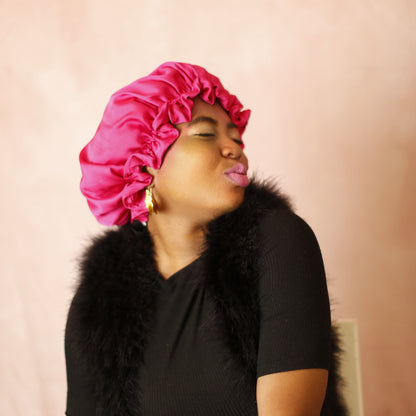 Woman wearing a pink satin bonnet against a pink background