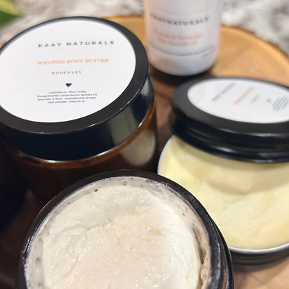 Jars of KAY Naturals whipped body butter on a wooden surface